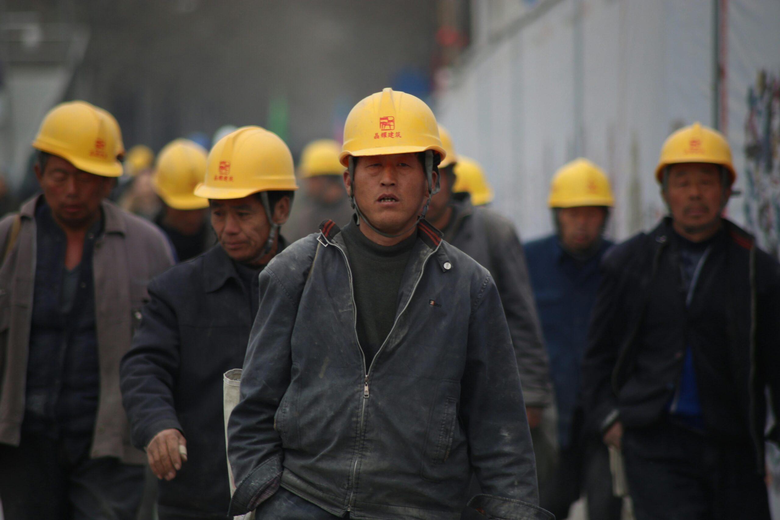 La población china “mantiene firmeza y calma” frente a la guerra comercial de Trump. Construction workers in hard hats walking at a site, highlighting teamwork and safety.